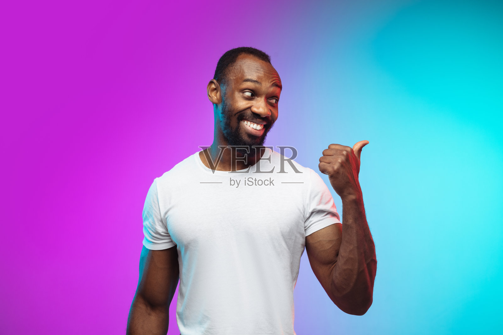 非裔美国年轻人的肖像在渐变工作室背景霓虹灯照片摄影图片