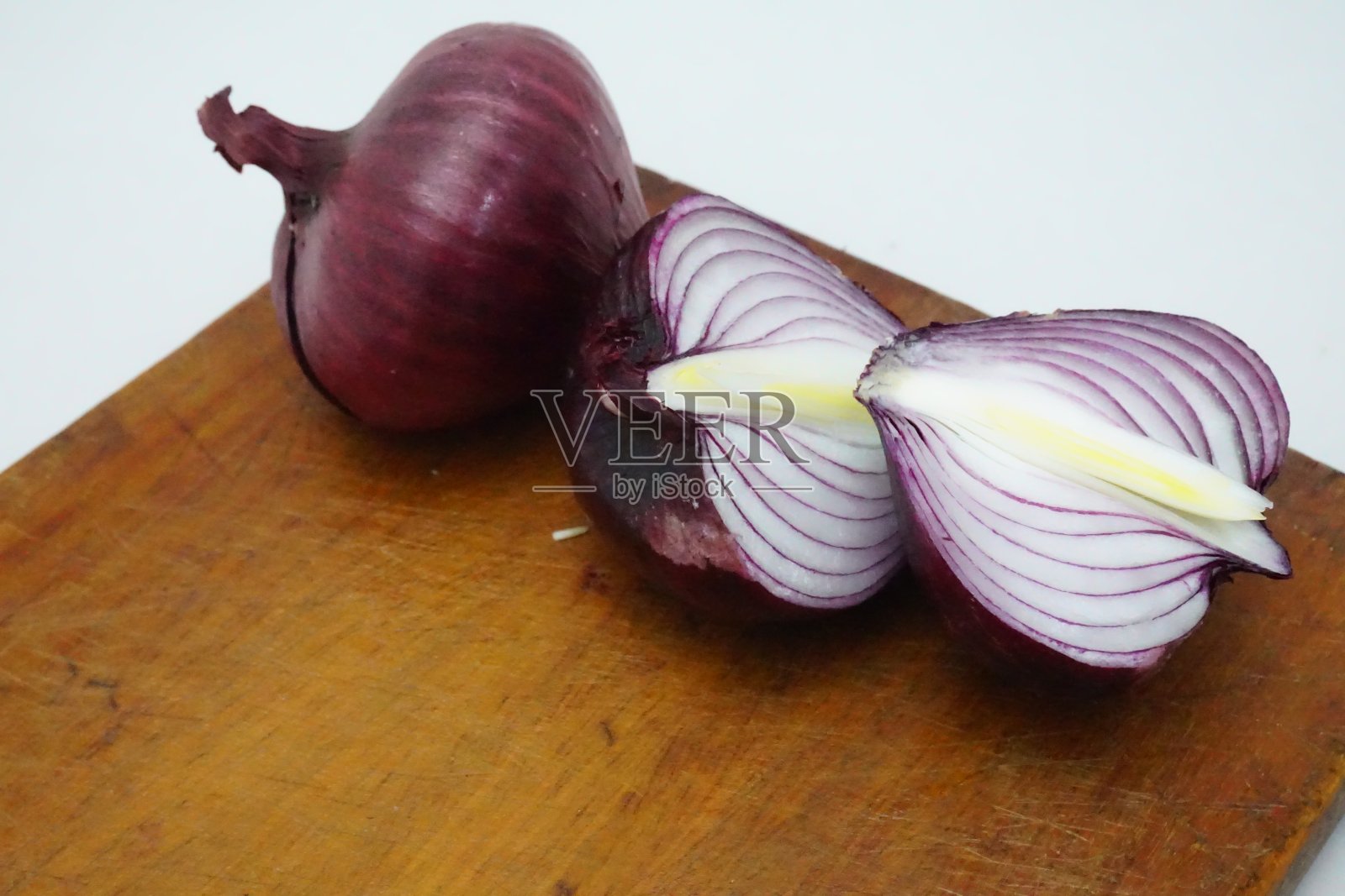 两个紫色的洋葱，红色的一个，一个切成两半，放在木板上，前景，两年生草本植物，淡黄色照片摄影图片
