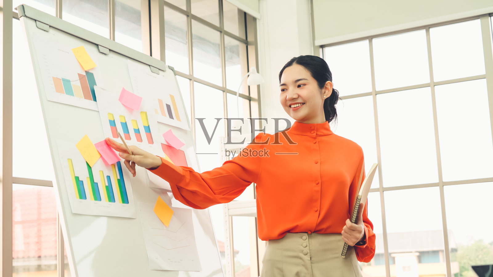 年轻女子在白板上解释商业数据照片摄影图片