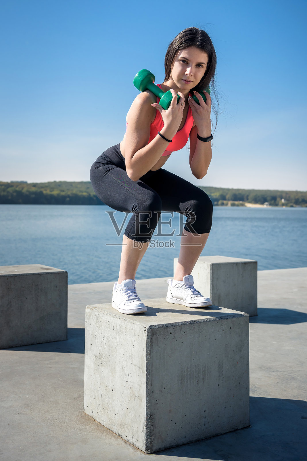一个健康的女孩在自然中拿着哑铃在湖边锻炼照片摄影图片