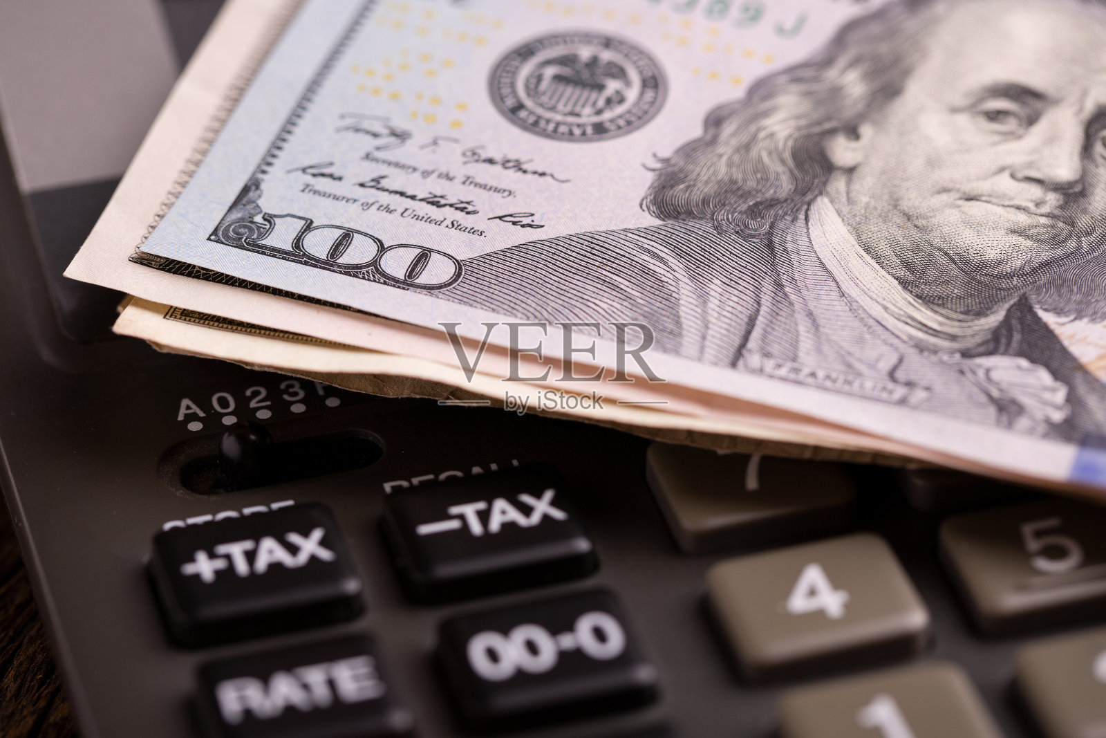 计算器和一百美元钞票。照片摄影图片