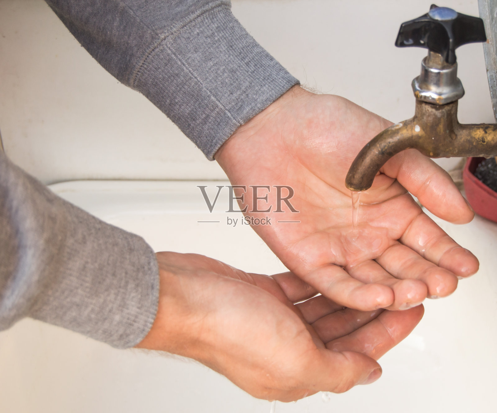 一名男子用来自一个古老的正宗铜水龙头的自来水洗手，夏天，户外，特写照片摄影图片