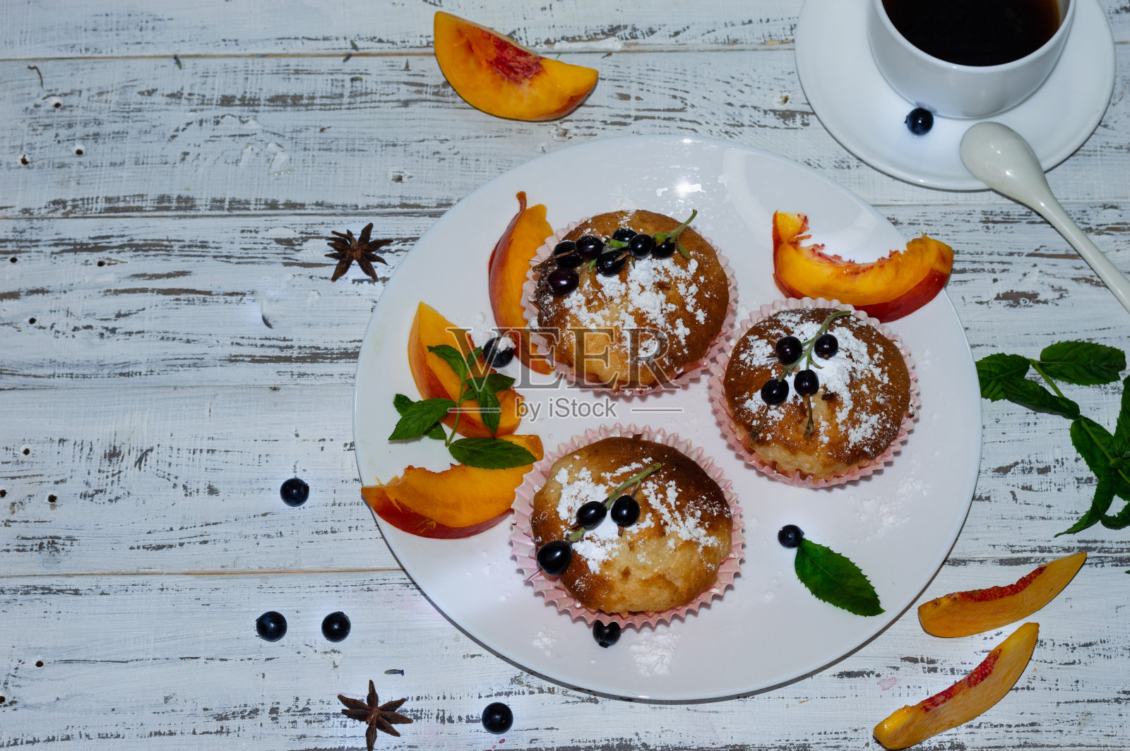 自制的小麦粉加糖粉，配上桃子和一种甜点葡萄，放在一个白色盘子里，配上一杯咖啡。普罗旺斯风格的白色木制背景上的构图。Macrophoto。副本的空间。照片摄影图片