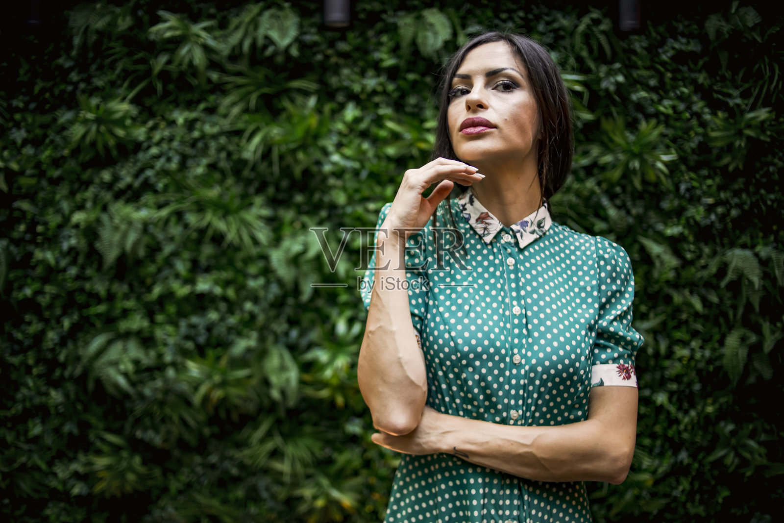 一个美丽的女模特站在一面墙的天然树叶照片摄影图片