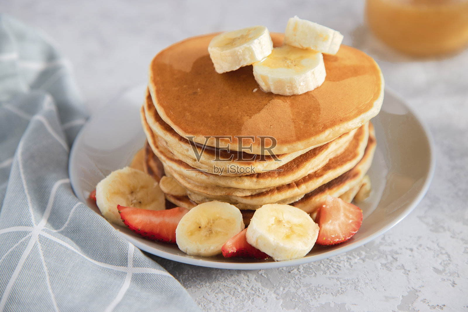 新鲜的自制煎饼和水果放在白色的盘子上，背景很亮。传统的早餐或甜点。照片摄影图片