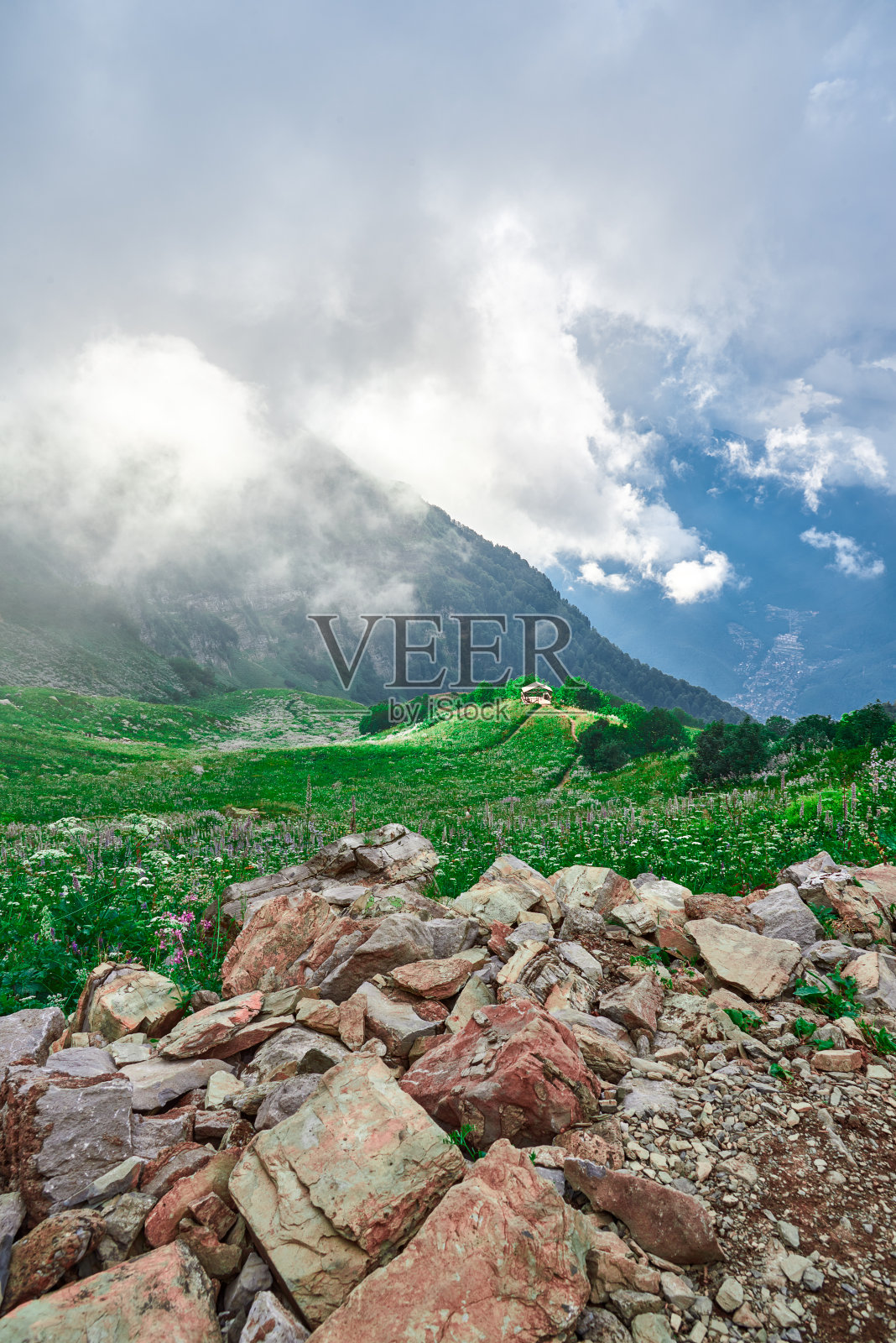 高海拔景观与温暖的傍晚光穿透低云，高山草和一个露台站在山坡上。照片摄影图片