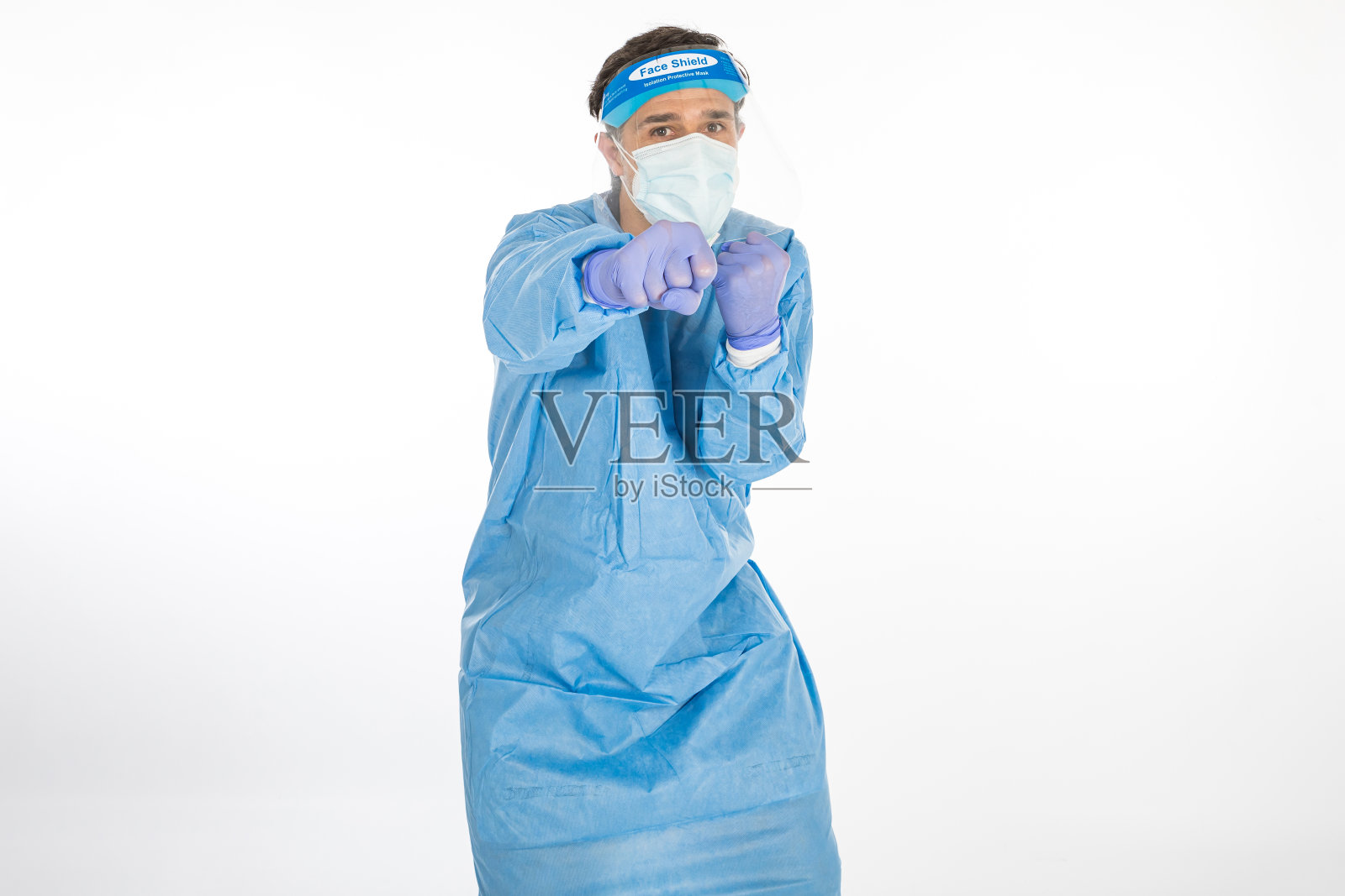 医生身穿蓝色防护装备抗击冠状病毒，准备战斗，背景为白色。战士。COVID医学概念照片摄影图片