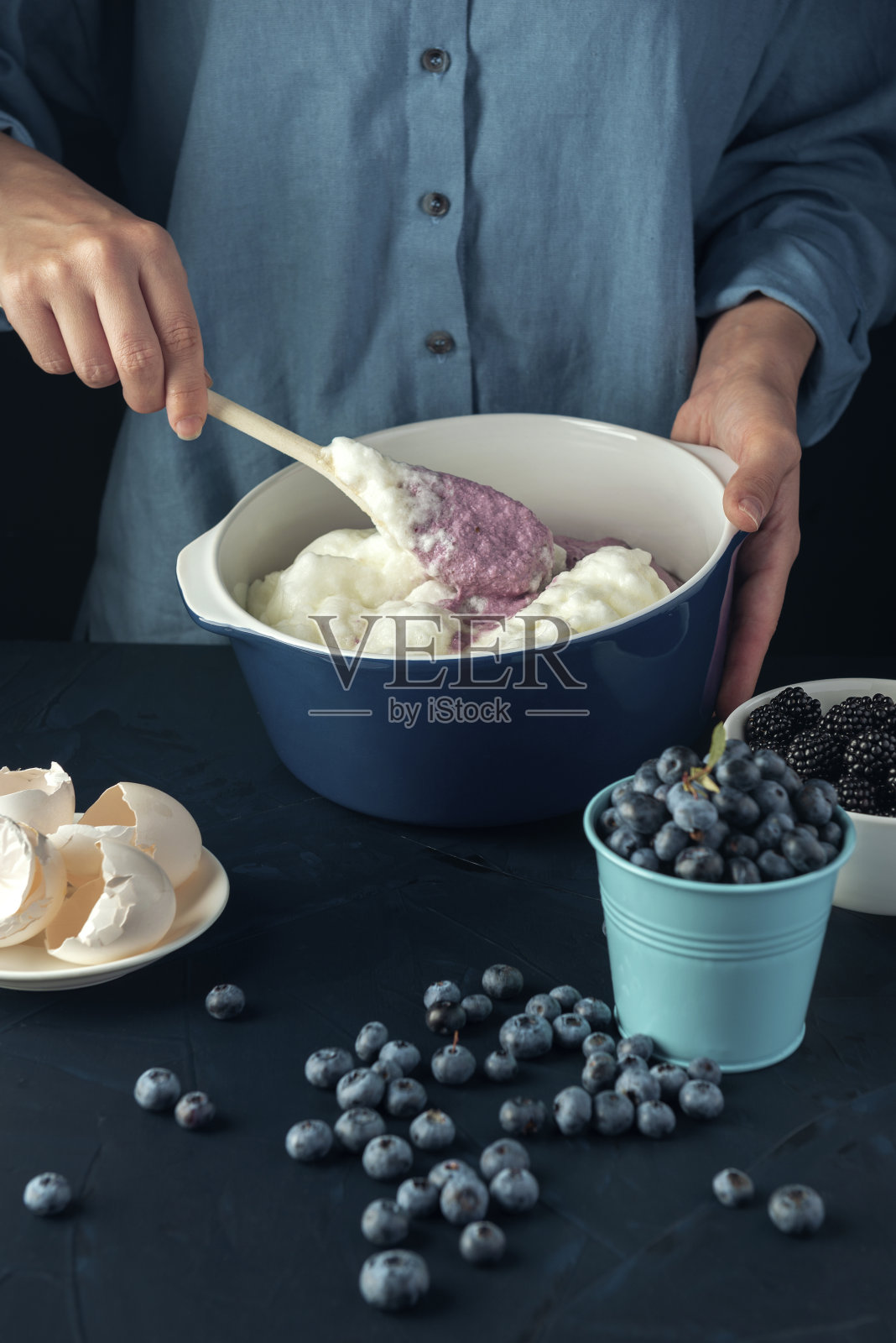 女人在混合浆果和白软干酪。烹饪过程。照片摄影图片