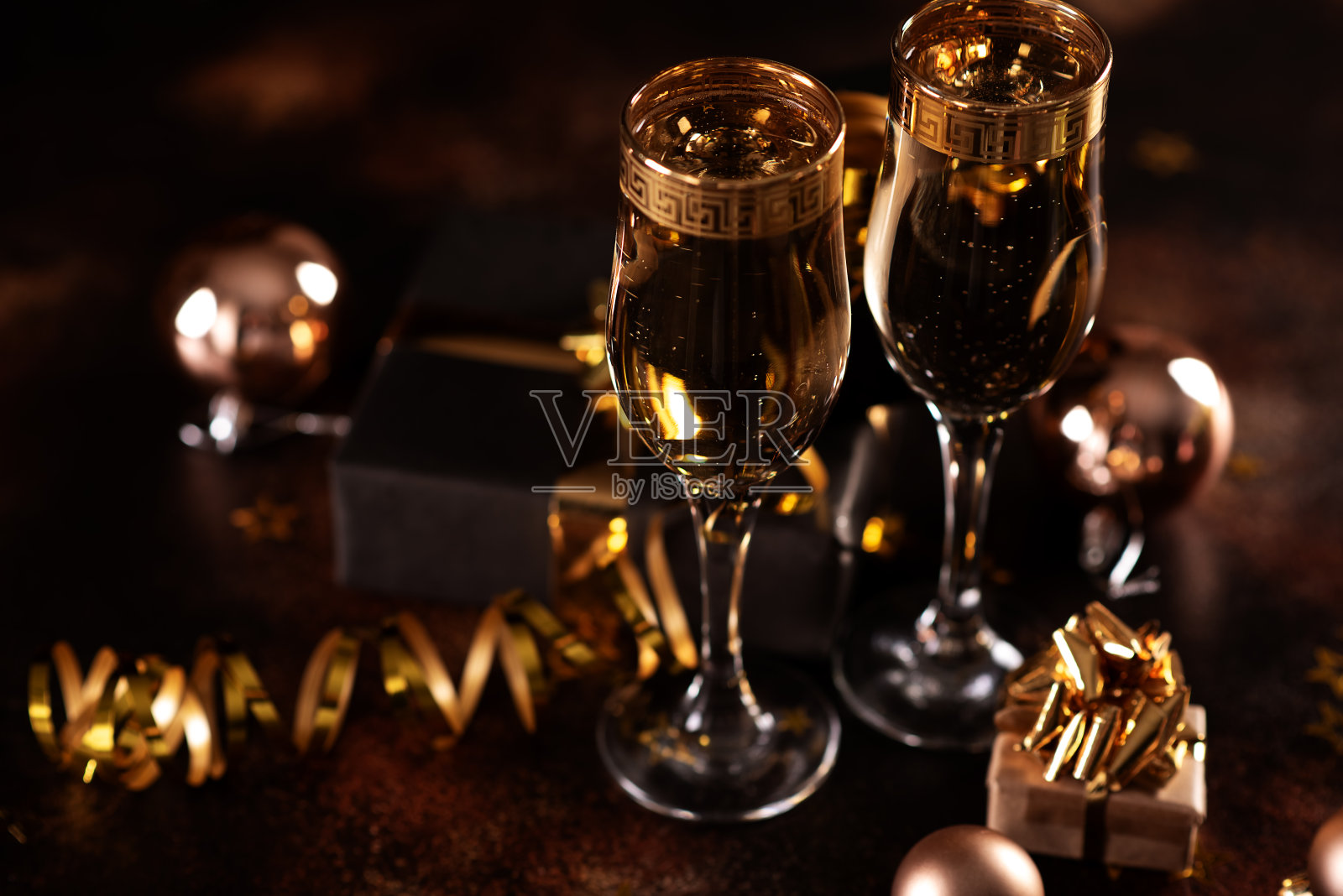 圣诞香槟、气泡、五彩纸屑和昏暗背景上模糊的灯光照片摄影图片