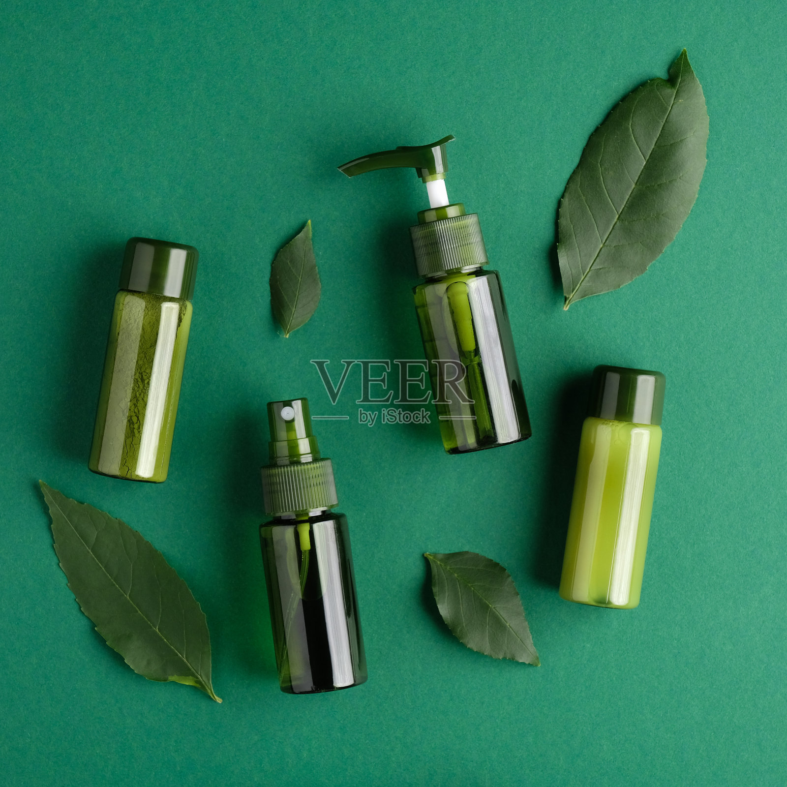 绿色化妆品瓶与植物叶子在绿色的背景。SPA天然有机美容产品，包装没有商标的品牌模型。平躺，俯视图。照片摄影图片