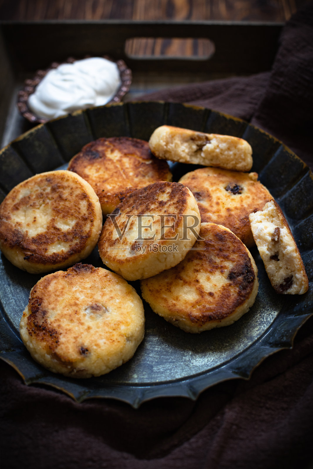 白软干酪薄烤饼，甜乳酪，意大利乳清干酪，葡萄干，酸奶油，老式盘子。暗的背景照片摄影图片