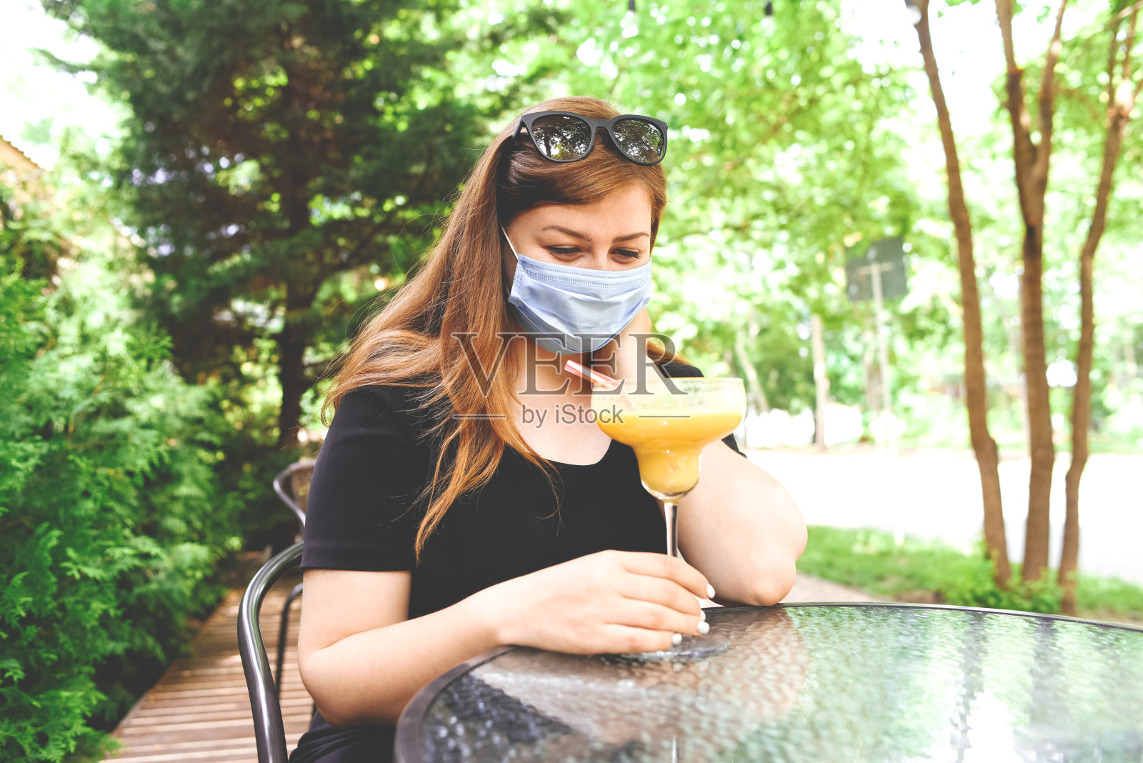 戴面具的女孩在想如何喝鸡尾酒。照片摄影图片