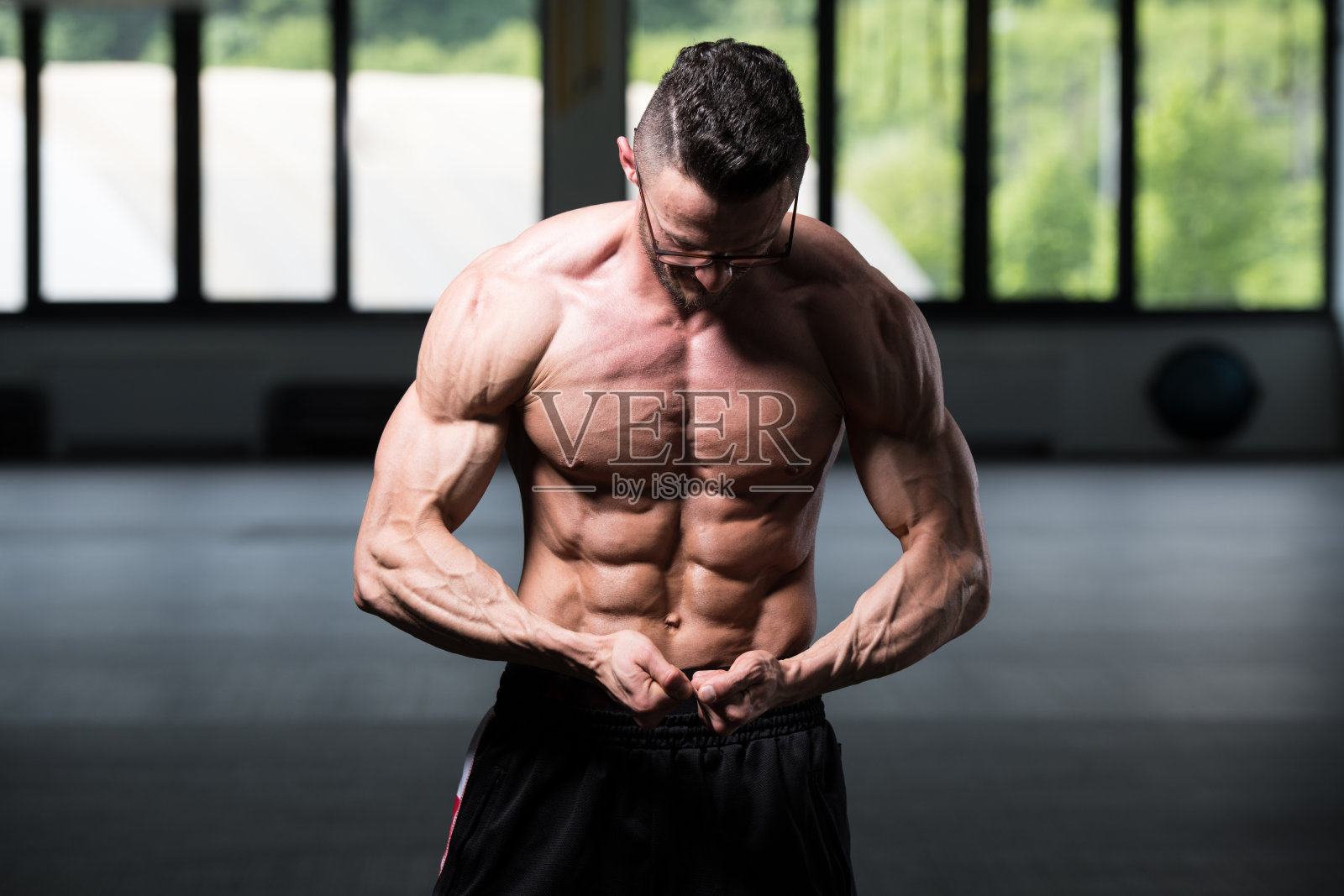 年轻的健美运动员戴眼镜锻炼肌肉照片摄影图片