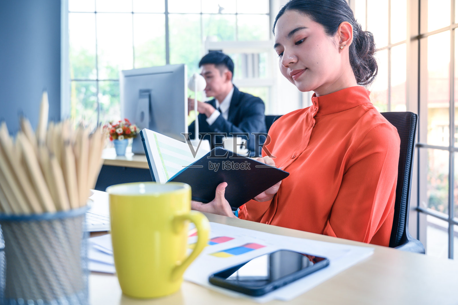 商务女性在办公场所拿着书。照片摄影图片