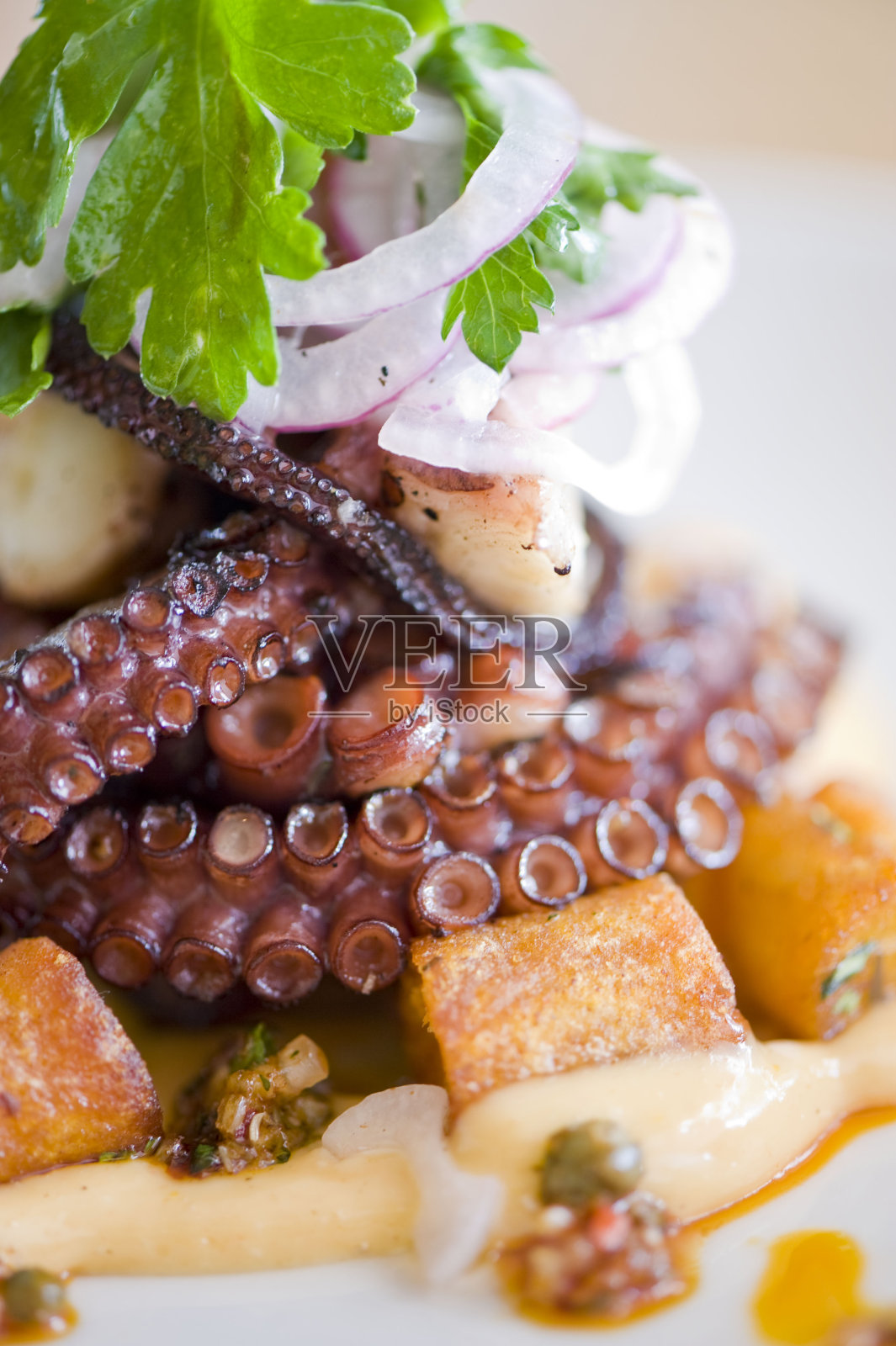 用橄榄油、黄油和大蒜煎烤章鱼，配以葱和意大利欧芹，并配以柠檬。经典的意大利，美国餐厅或法国小酒馆的主菜或开胃菜。照片摄影图片