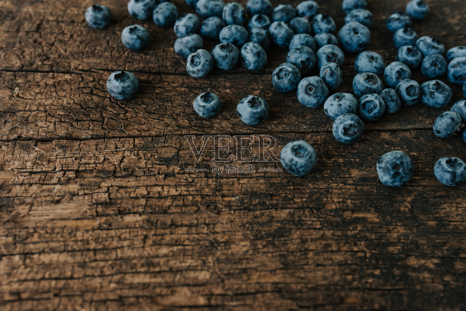 新鲜的蓝莓散落在一张木桌上。照片摄影图片