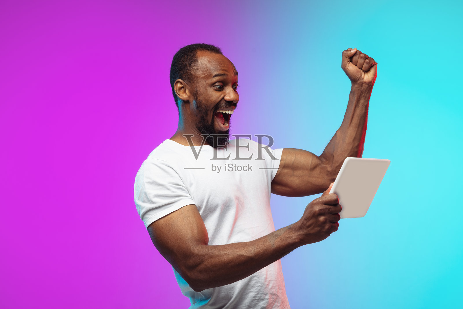 非裔美国年轻人的肖像在渐变工作室背景霓虹灯照片摄影图片