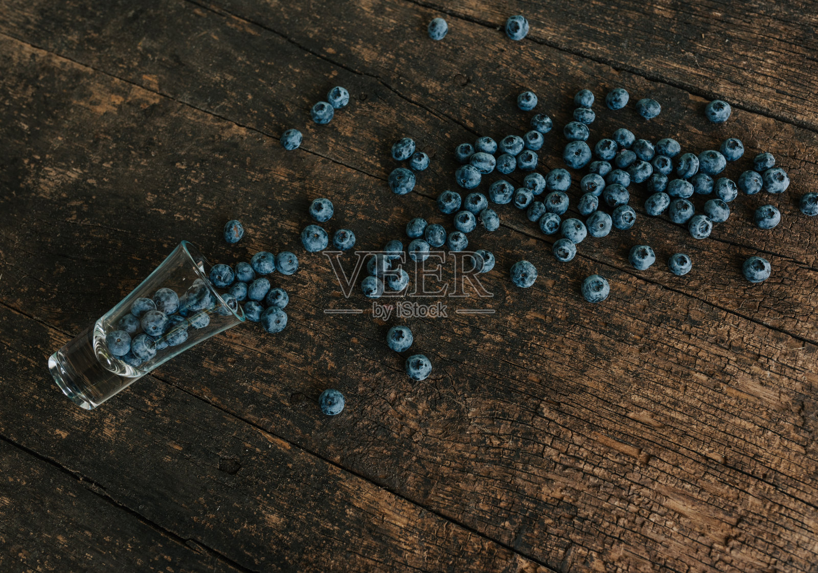 蓝莓装在一个透明的玻璃杯里，然后分散照片摄影图片