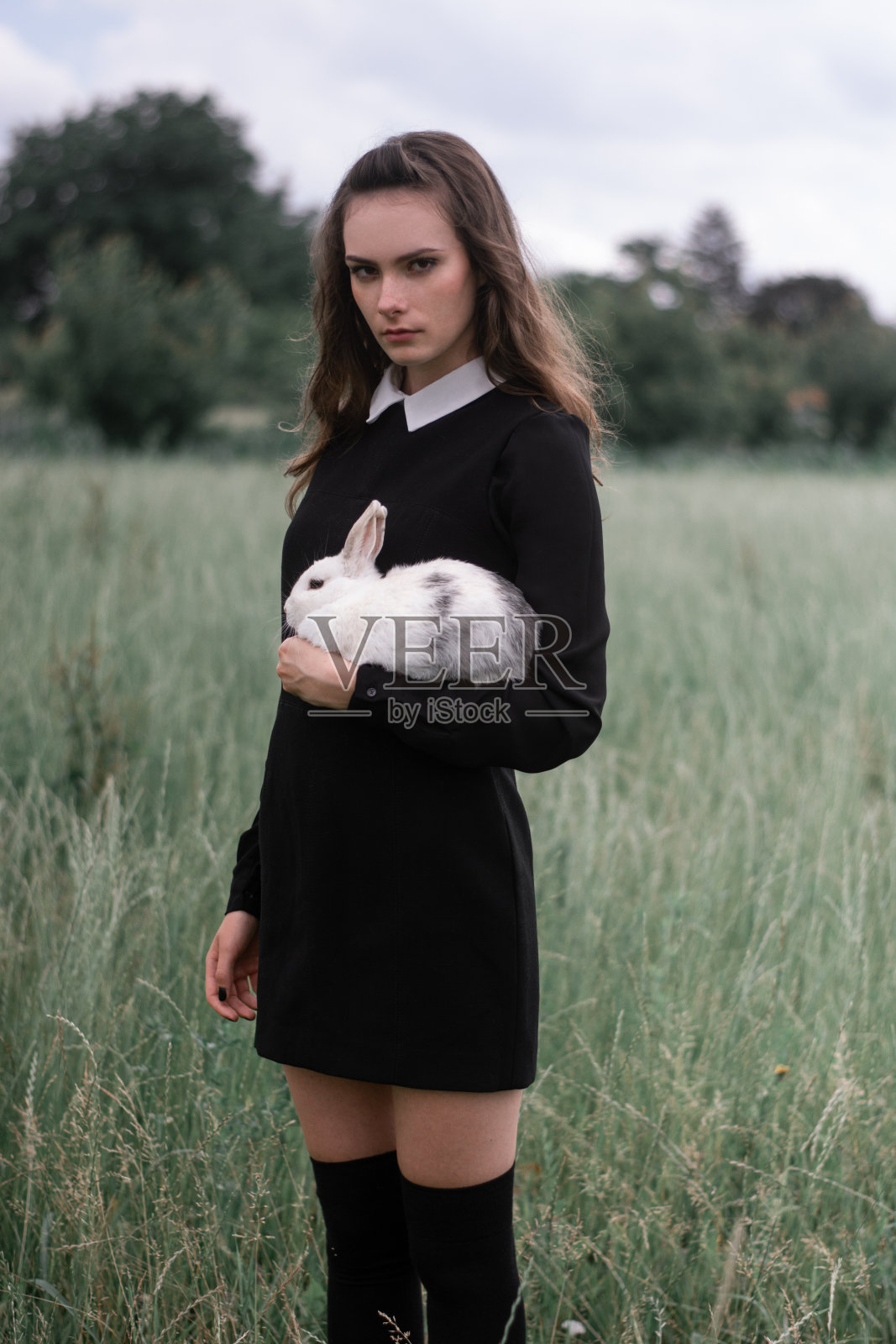 美丽的女孩抱着小白兔在大自然中摆姿势照片摄影图片