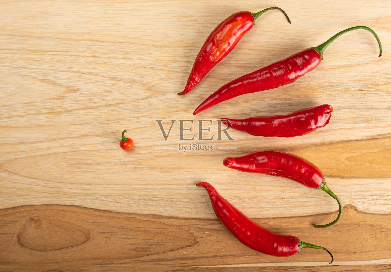 胡椒粉“Dedo de moça”在抛光的木头和绿色桌布上的桌子，俯视图。照片摄影图片