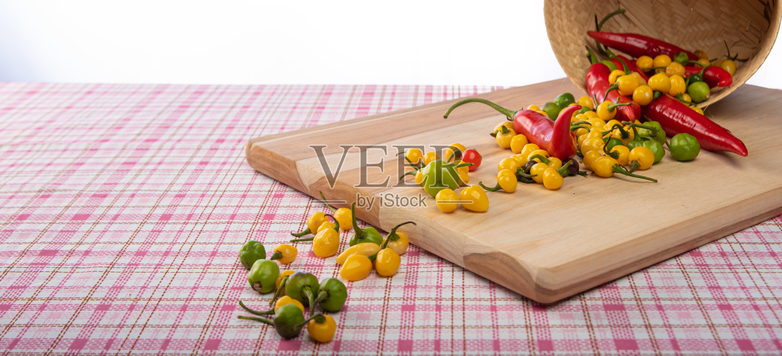 有颜色的辣椒从篮子里掉到桌上，有选择性地集中。照片摄影图片