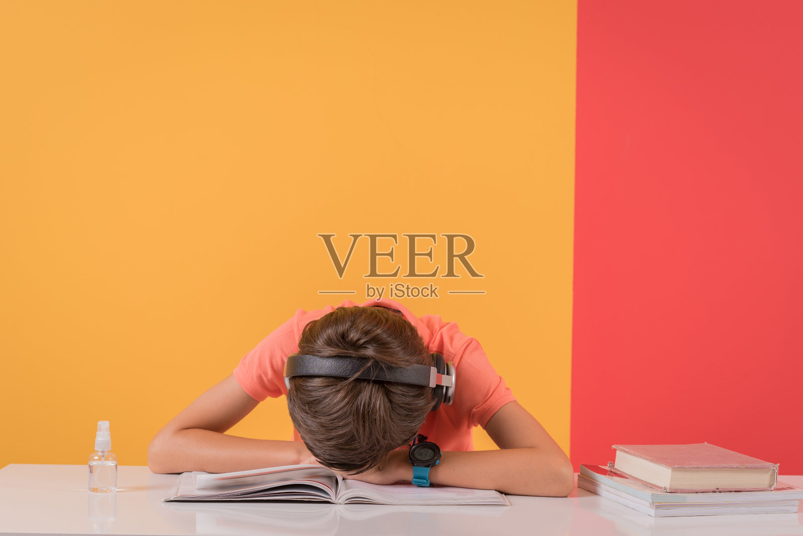 小男孩厌倦了做作业，趴在桌子上打瞌睡。照片摄影图片