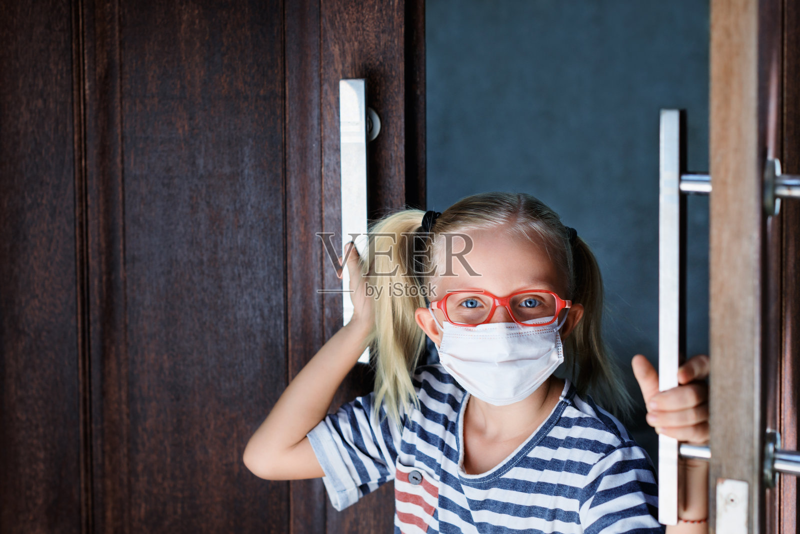 戴着面罩的孩子从门外偷看照片摄影图片