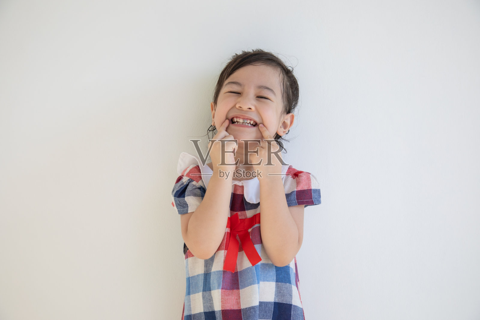 一个可爱的四岁亚洲女孩微笑着在镜头前表演。任何看到的人都会因为积极的想法而感到光明和快乐。在工作室里用白色背景拍摄半身像，并留有复制空间。照片摄影图片