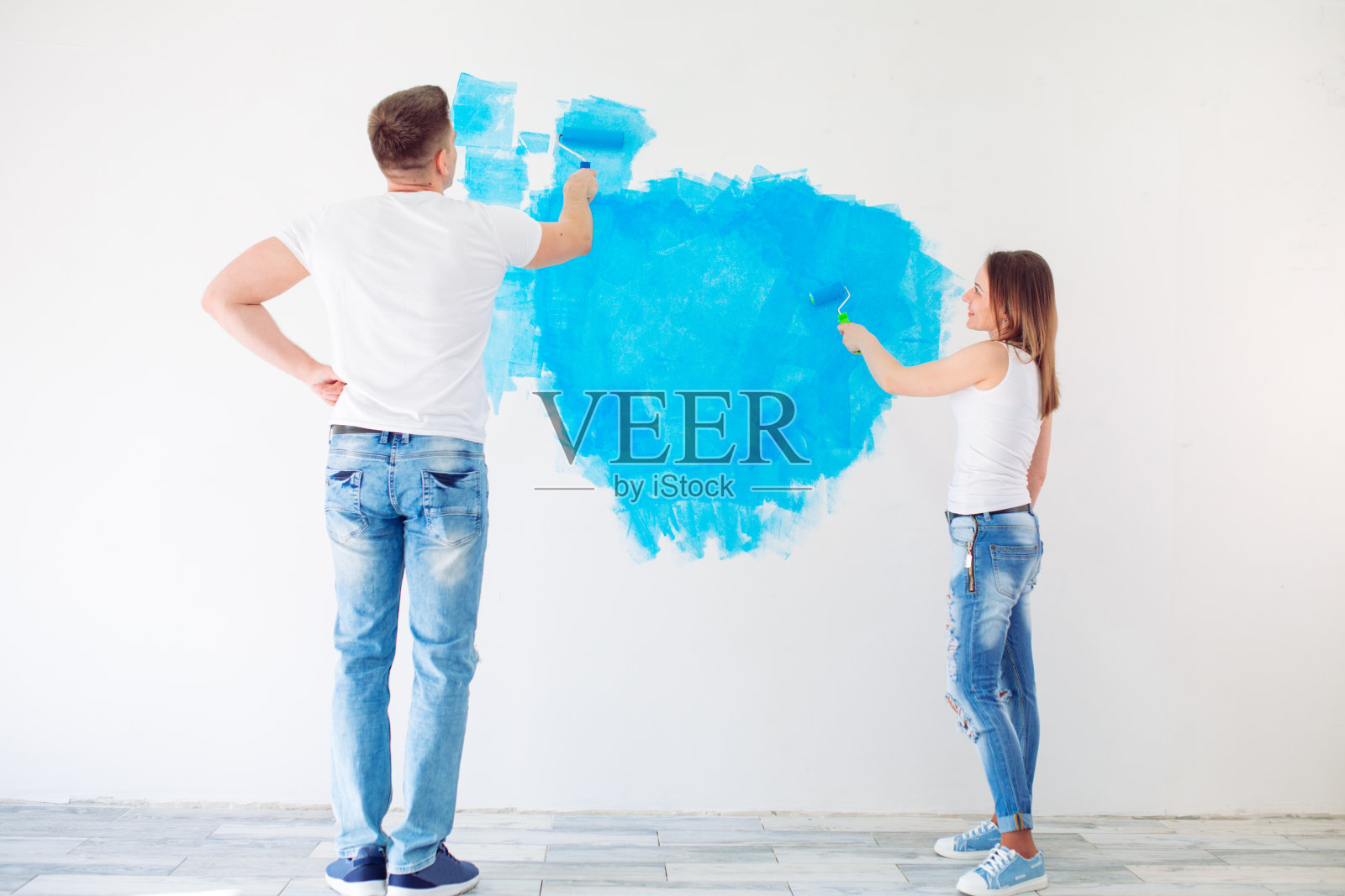 快乐的夫妇在他们的新房子粉刷墙壁准备住在一起。照片摄影图片