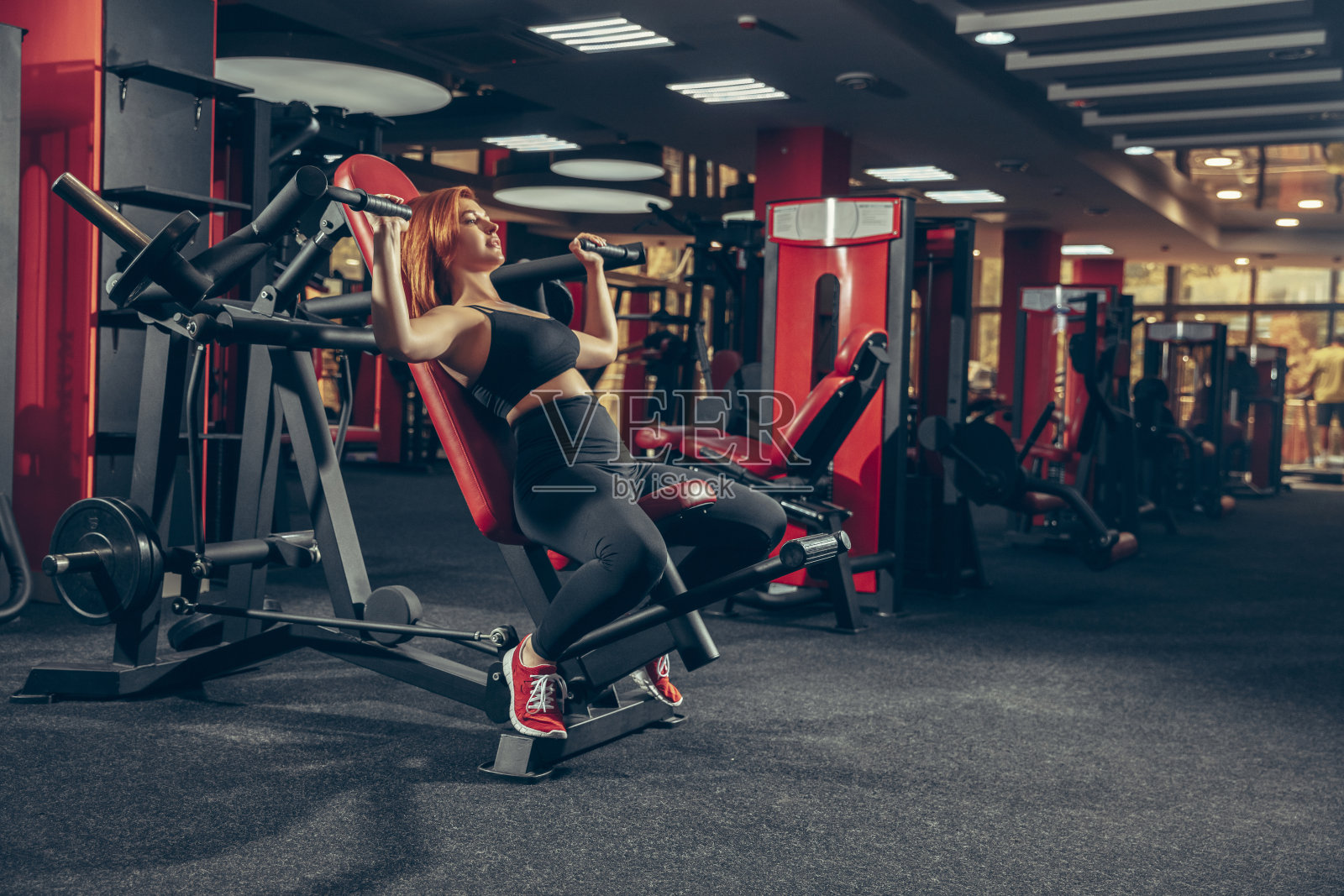 年轻的肌肉发达的白人妇女在健身房用器材练习。健康，健康的生活方式，健身。照片摄影图片