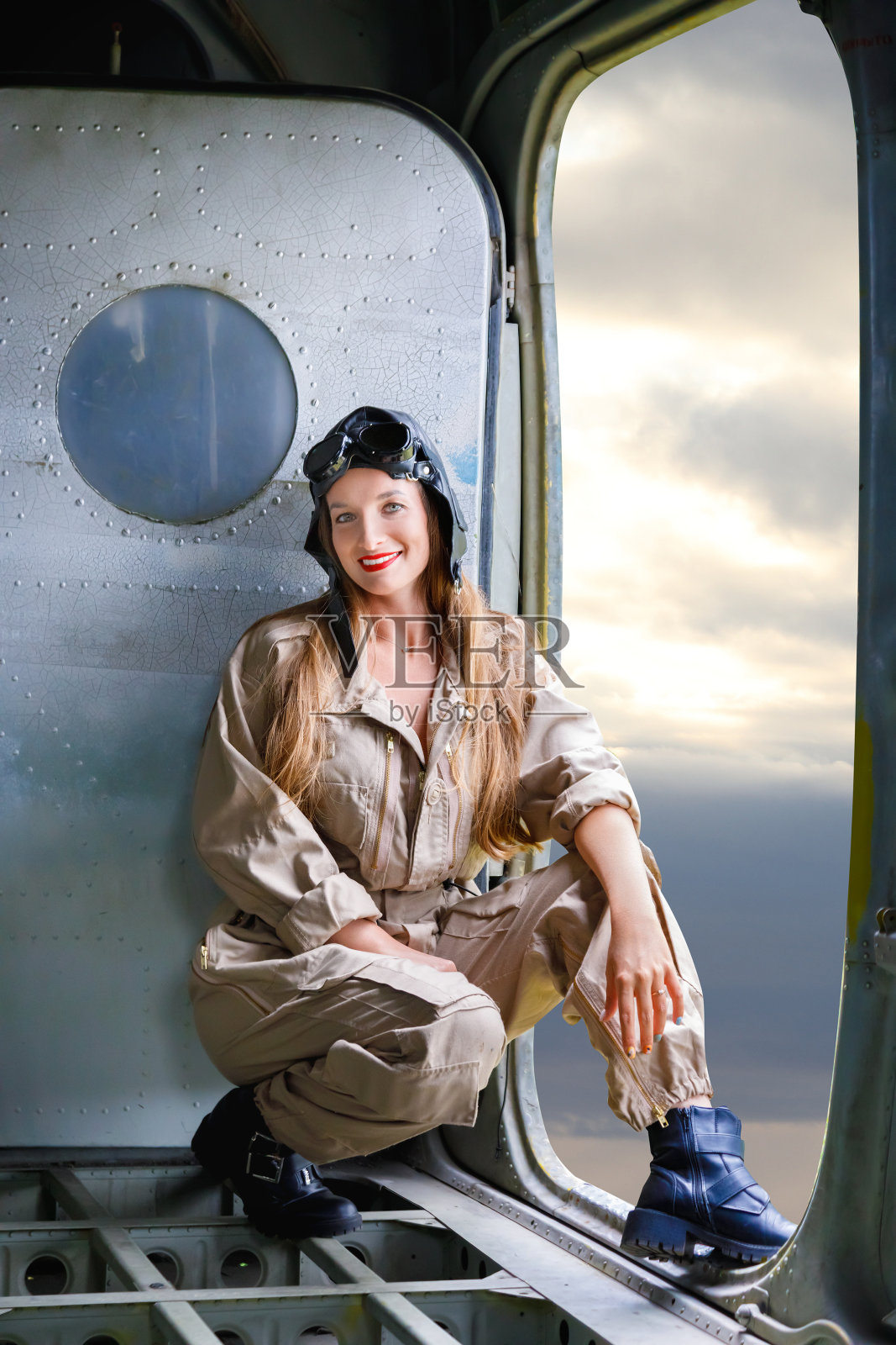 一名身穿飞行员服的年轻女子坐在飞机内打开的舱门旁照片摄影图片