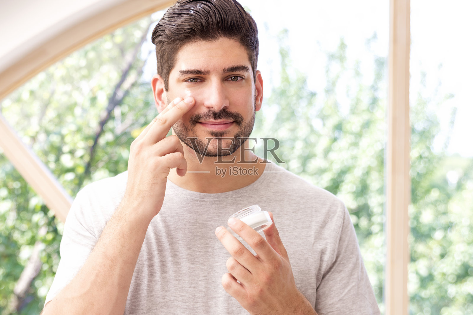 一名男子站在浴室里往脸上涂面霜照片摄影图片