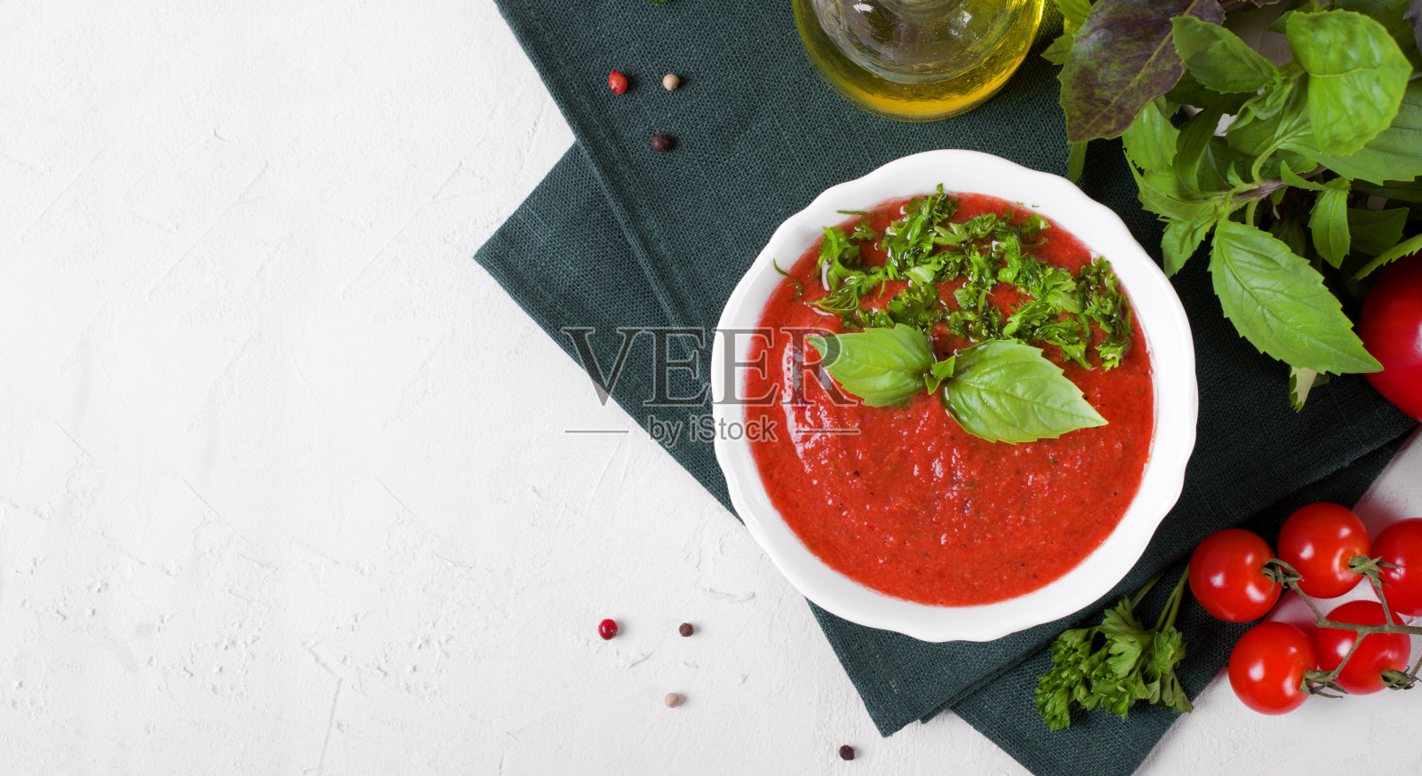 用陶瓷碗盛番茄凉菜汤，上面铺上罗勒叶照片摄影图片