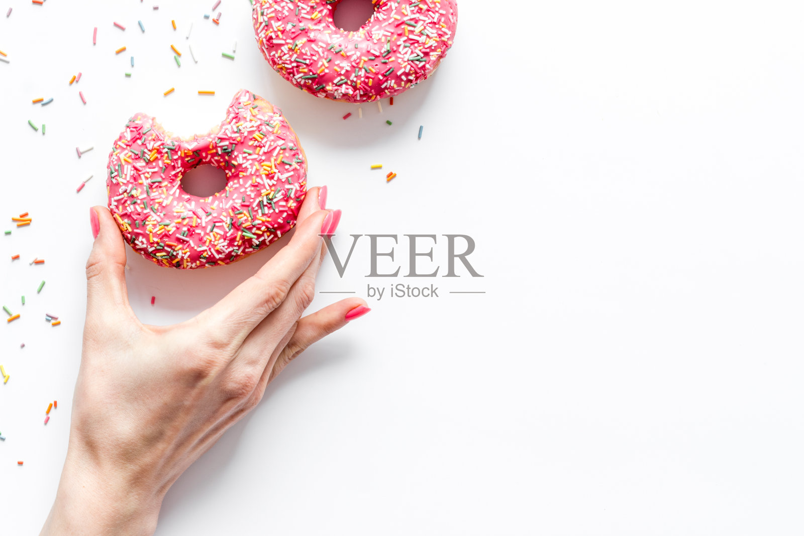 粉红色的浆果甜甜圈平躺着，俯视图。上釉和撒糖的甜甜圈照片摄影图片