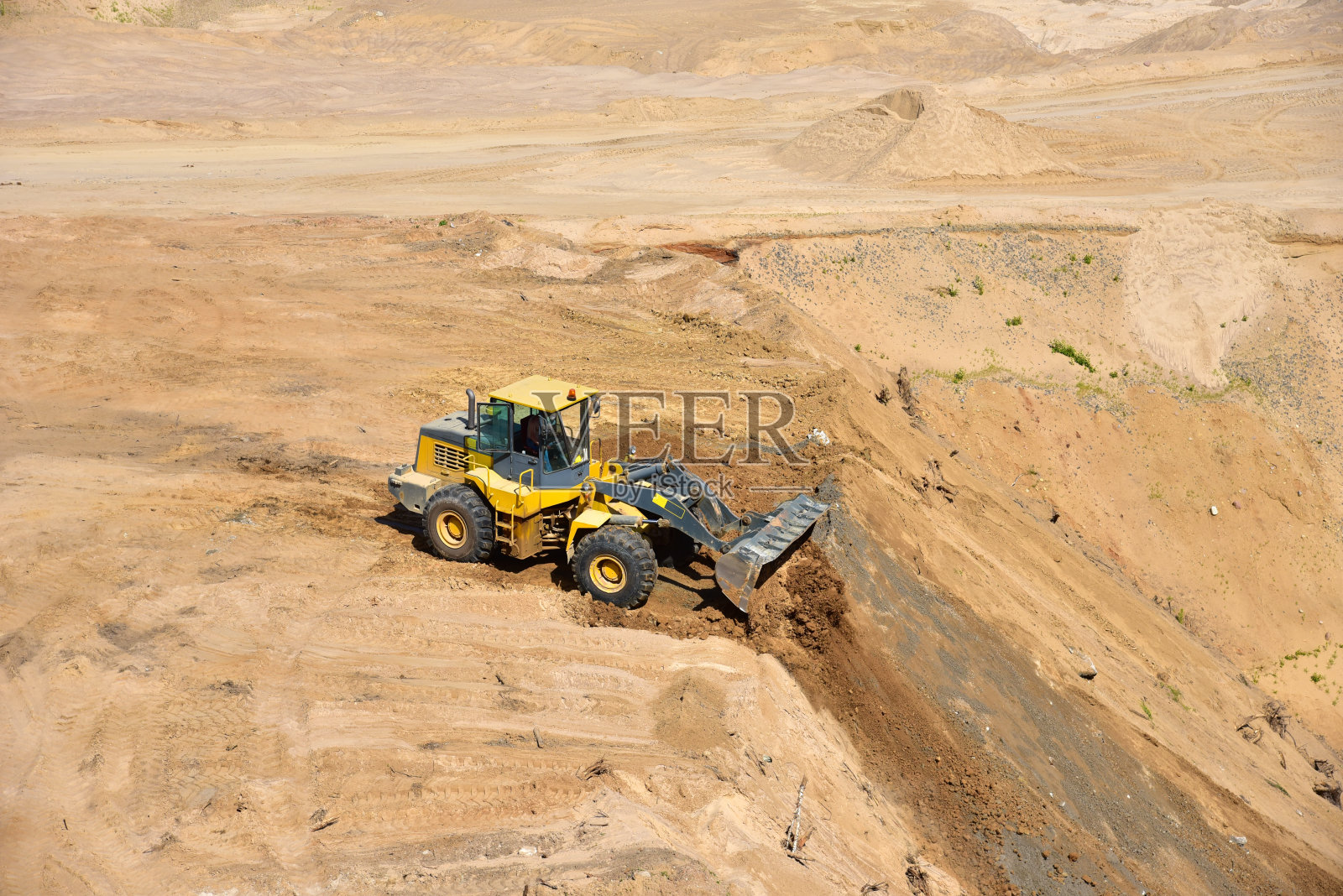 前端装载机正在恢复露天矿周围的景观。土地恢复过程。采砂完成后进行矿山复垦照片摄影图片