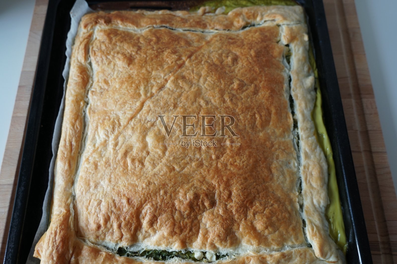 用菠菜，羊乳酪和鸡蛋调味，用牛至，盐，黑胡椒，肉豆蔻和切碎的洋葱在长方形烤盘上烤。照片摄影图片