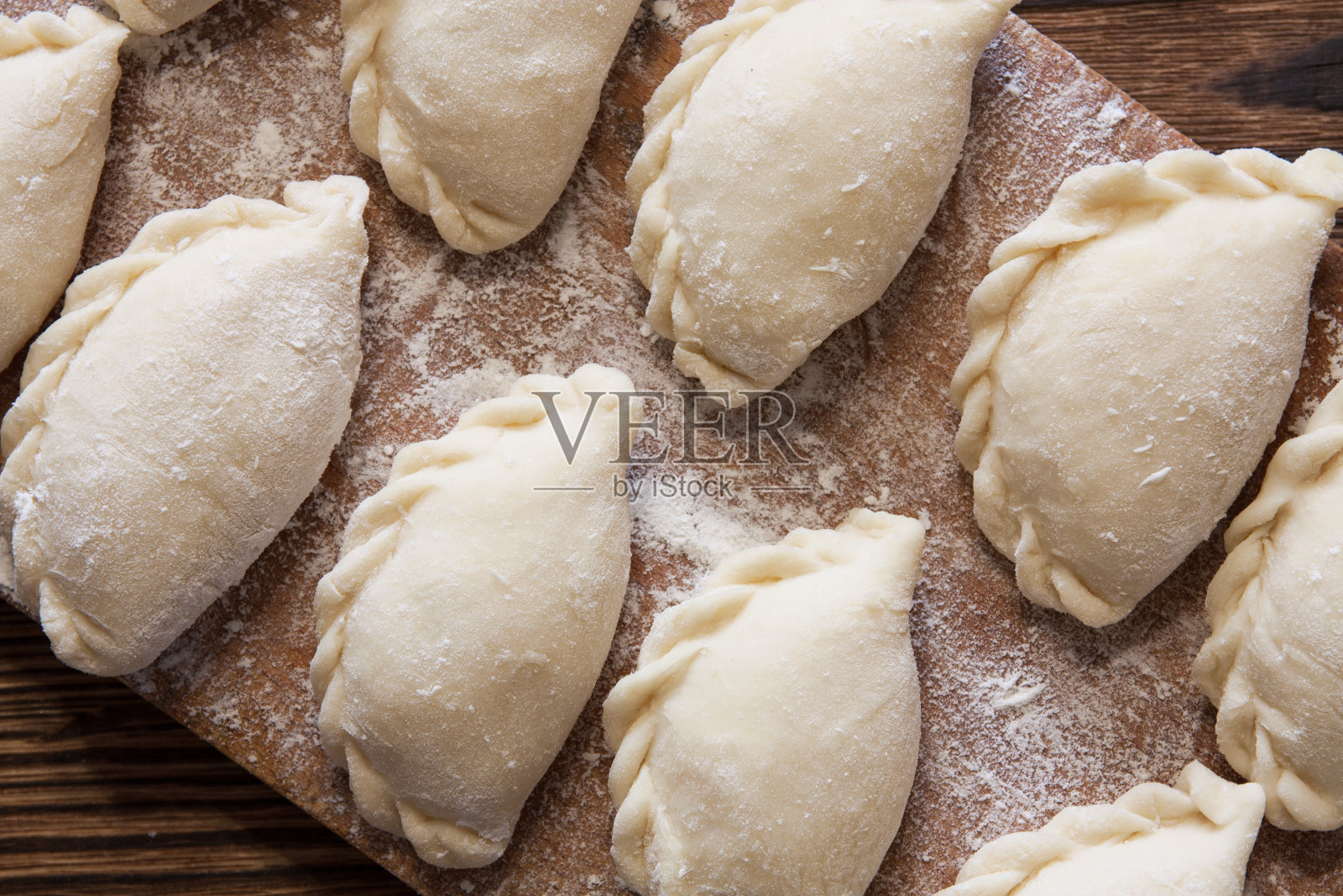 准备用于烹饪的vareniki，饺子，pierogi在面粉木板上-传统乌克兰食品。有选择性的重点照片摄影图片