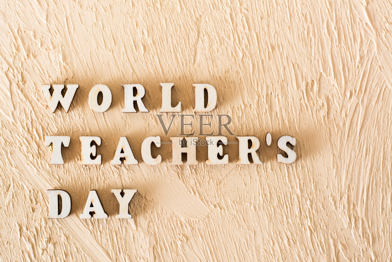 世界教师日。文字由木质字母在纹理米色石膏背景照片摄影图片
