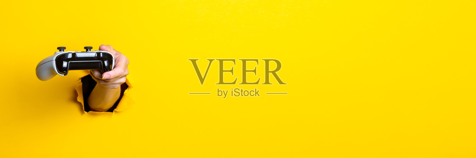 在亮黄色背景下，女性手握操纵杆。横幅。照片摄影图片