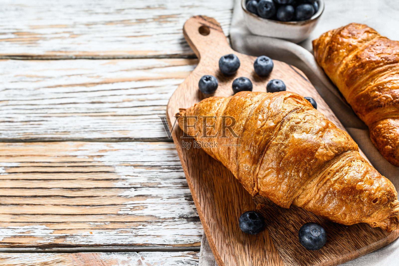 美味的早餐，新鲜牛角面包和蓝莓。白色木制背景。前视图。本空间照片摄影图片