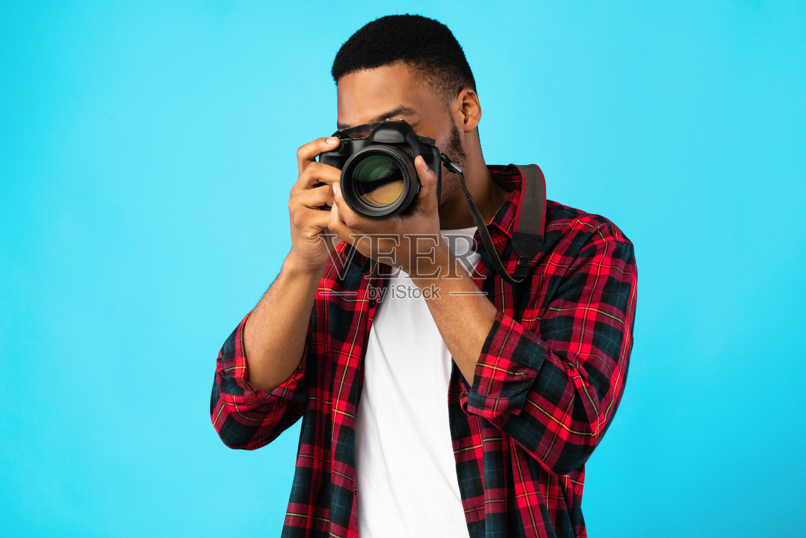 非洲裔美国摄影师站在蓝色背景上拍照照片摄影图片