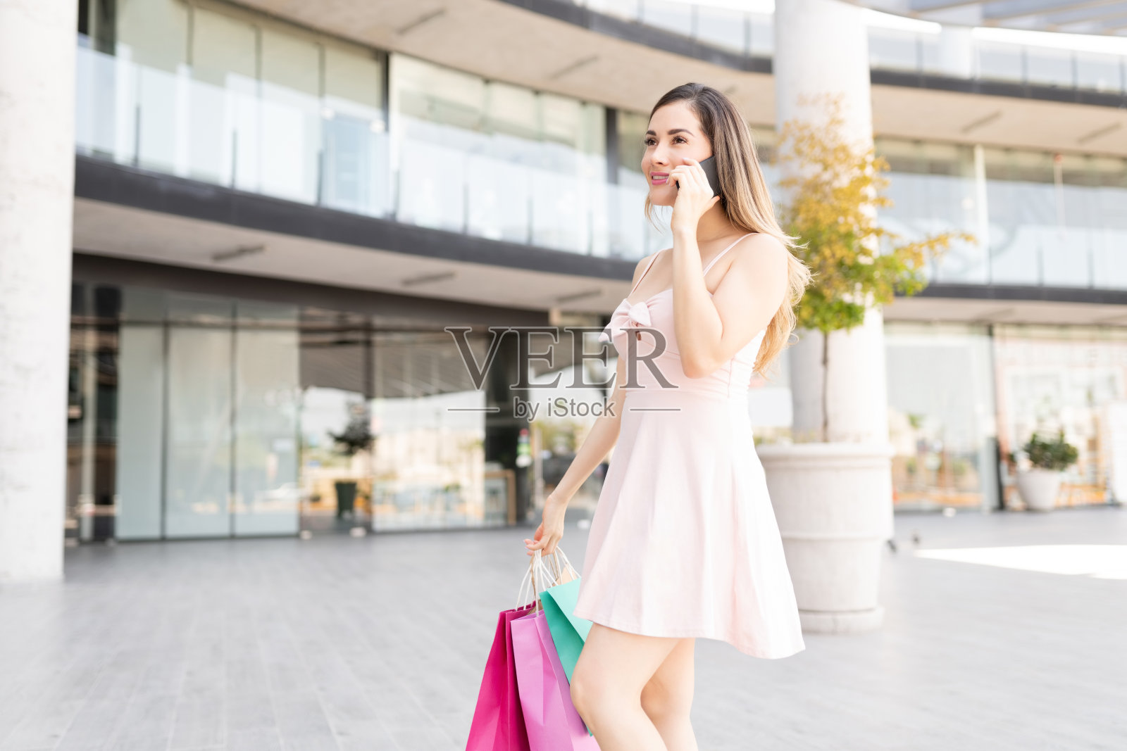 拿着购物袋微笑的女人在用智能手机聊天照片摄影图片