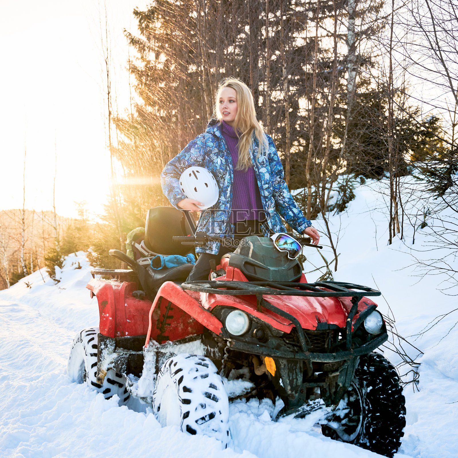 美丽的金发女孩与红色的ATV在冬天的山区照片摄影图片