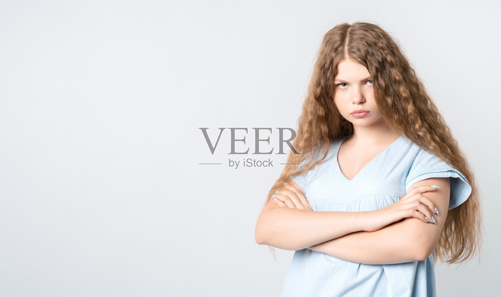 沉思的卷发女孩，双手交叉，看向镜头照片摄影图片