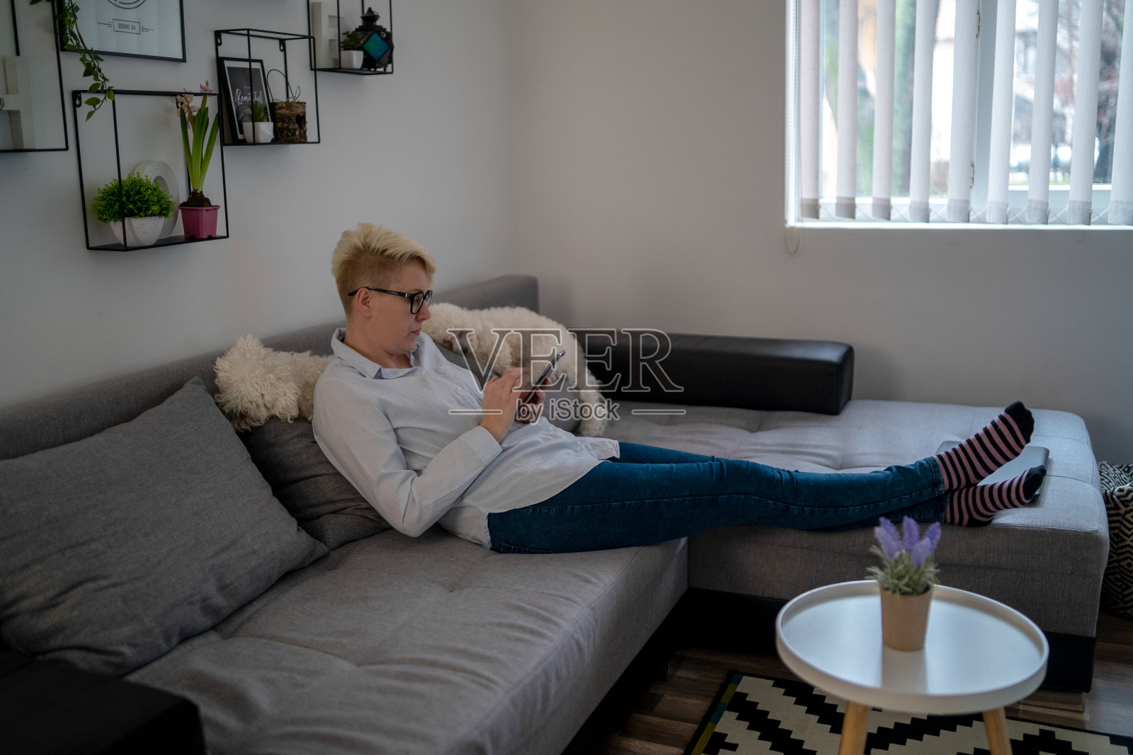 一名妇女在家里使用智能手机，而机器人吸尘器正在工作照片摄影图片