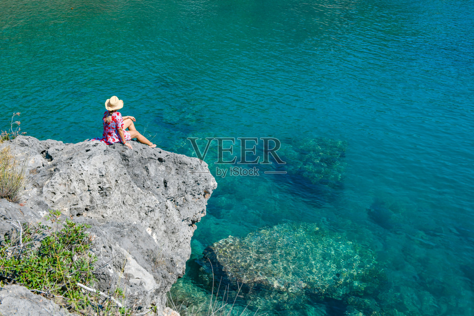 一个女人坐在海滩上看着大海。照片摄影图片
