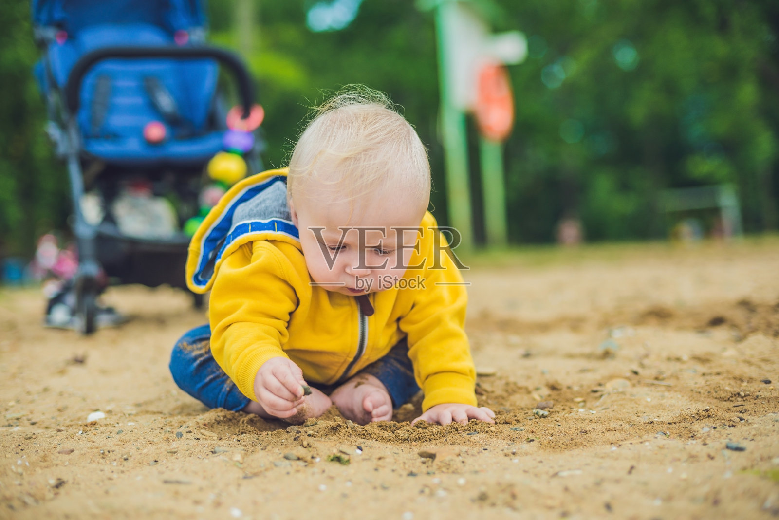 蹒跚学步的小男孩在沙滩上玩沙子，发展精细的运动技能照片摄影图片