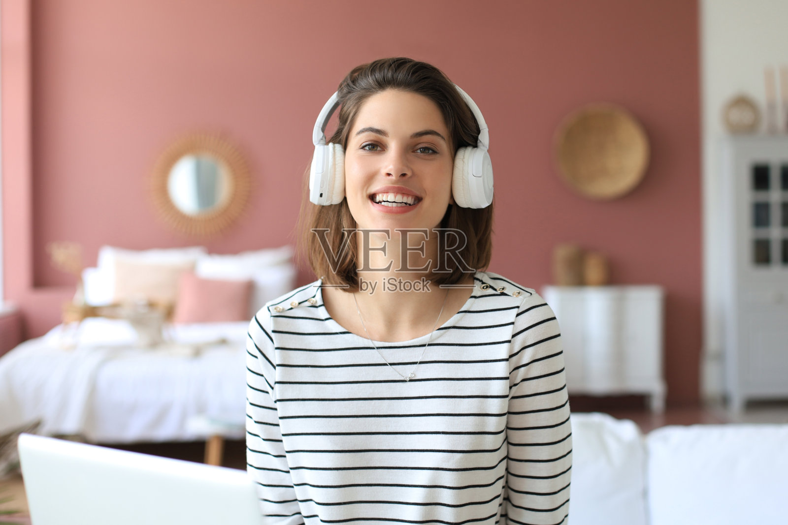 美丽的黑发女人戴着耳机坐在沙发上闭着眼睛听音乐。照片摄影图片