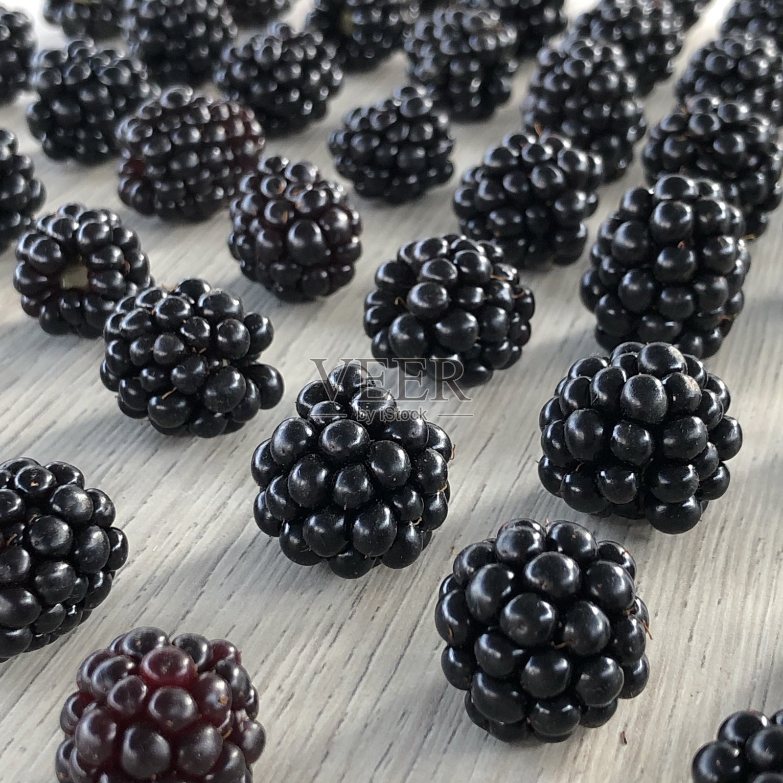 一个成熟的黑莓躺在桌子上的图像，各种各样的组合特写照片摄影图片