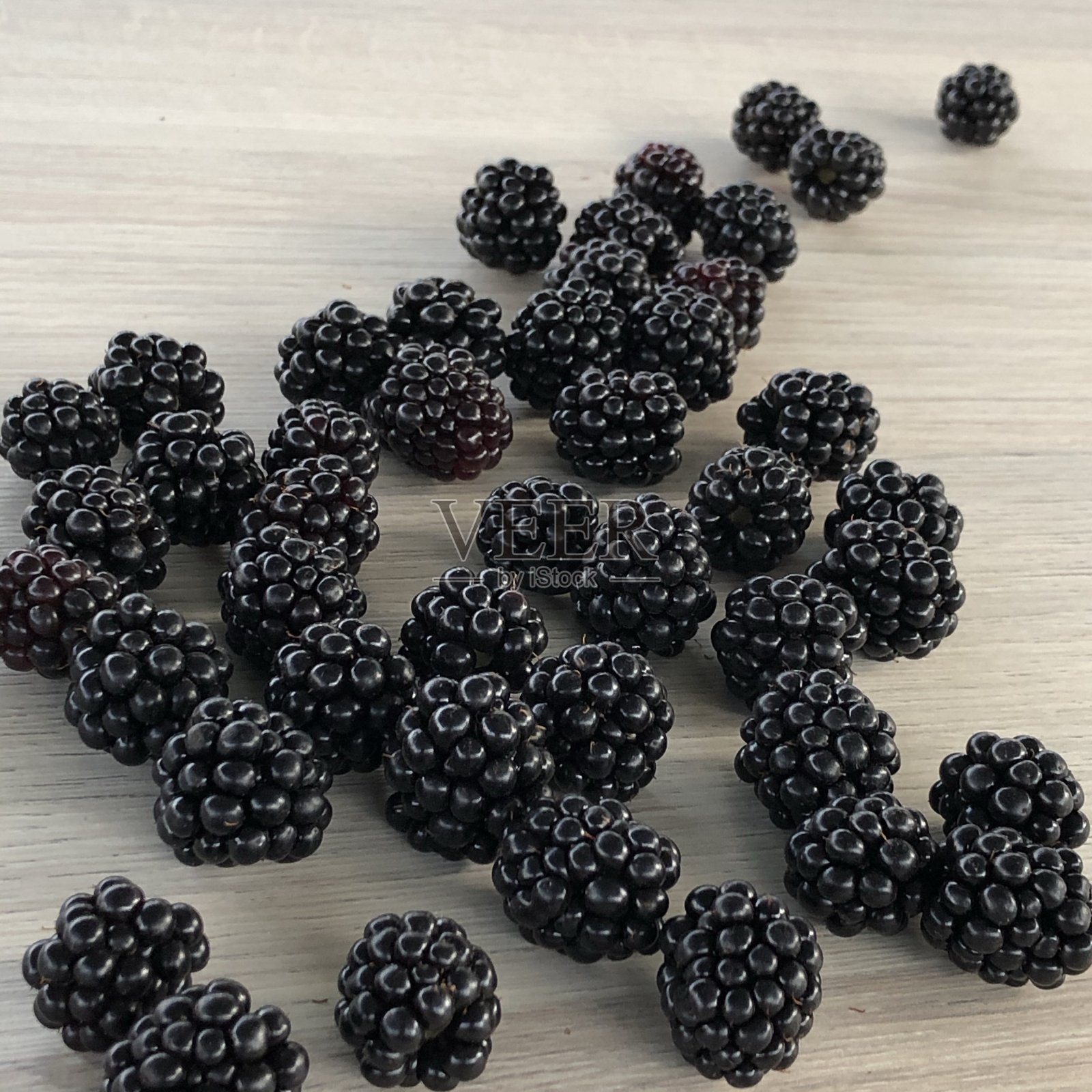 一个成熟的黑莓躺在桌子上的图像，各种各样的组合特写照片摄影图片